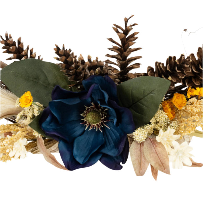 Details of a decorative wreath made of twigs and adorned with artificial blue and yellow flowers and beige accents.