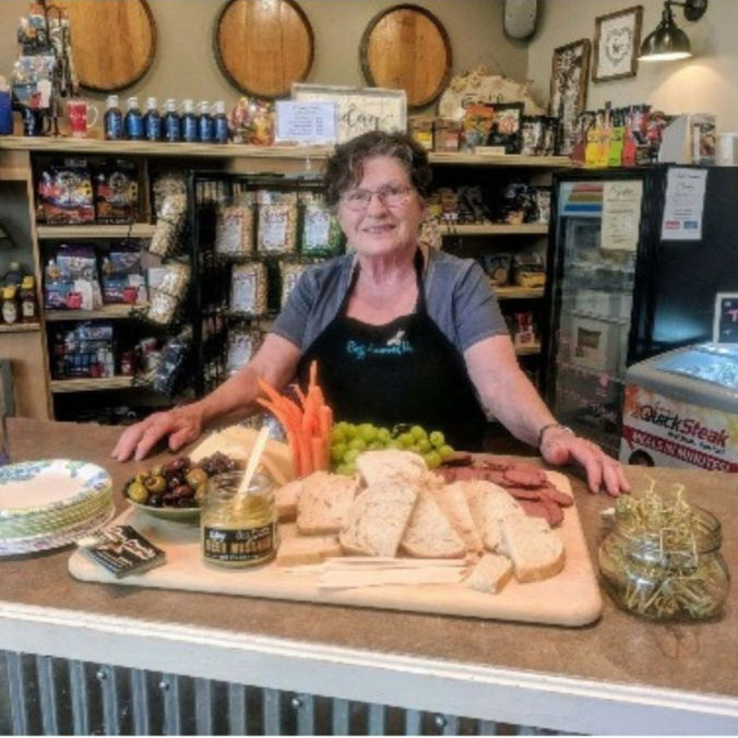Betty, CEO of Buzz Savories standing and sampling next to her product.