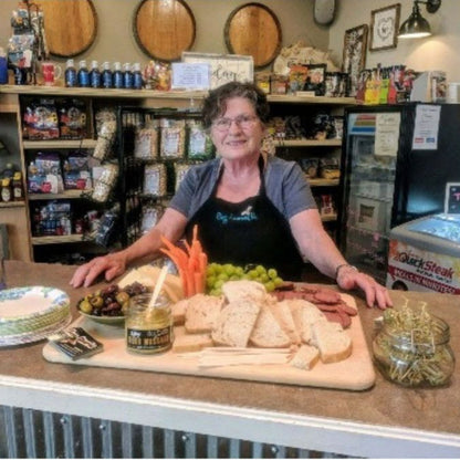 Betty, CEO of Buzz Savories standing and sampling next to her product.